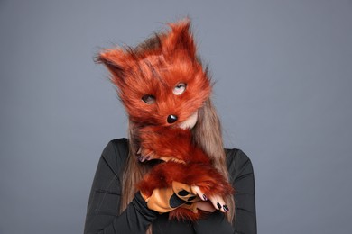 Quadrobics. Girl wearing fox mask and gloves on grey background