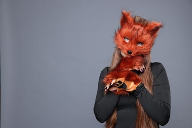 Photo of Quadrobics. Girl wearing fox mask and gloves on grey background, space for text