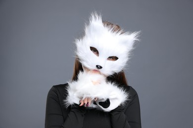 Photo of Quadrobics. Girl wearing cat mask and gloves on grey background