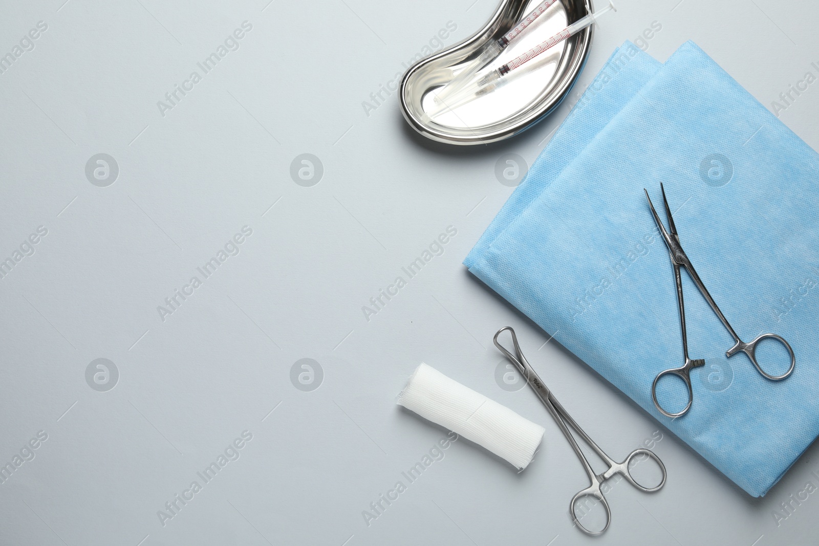 Photo of Different surgical instruments and gauze on light grey background, flat lay. Space for text