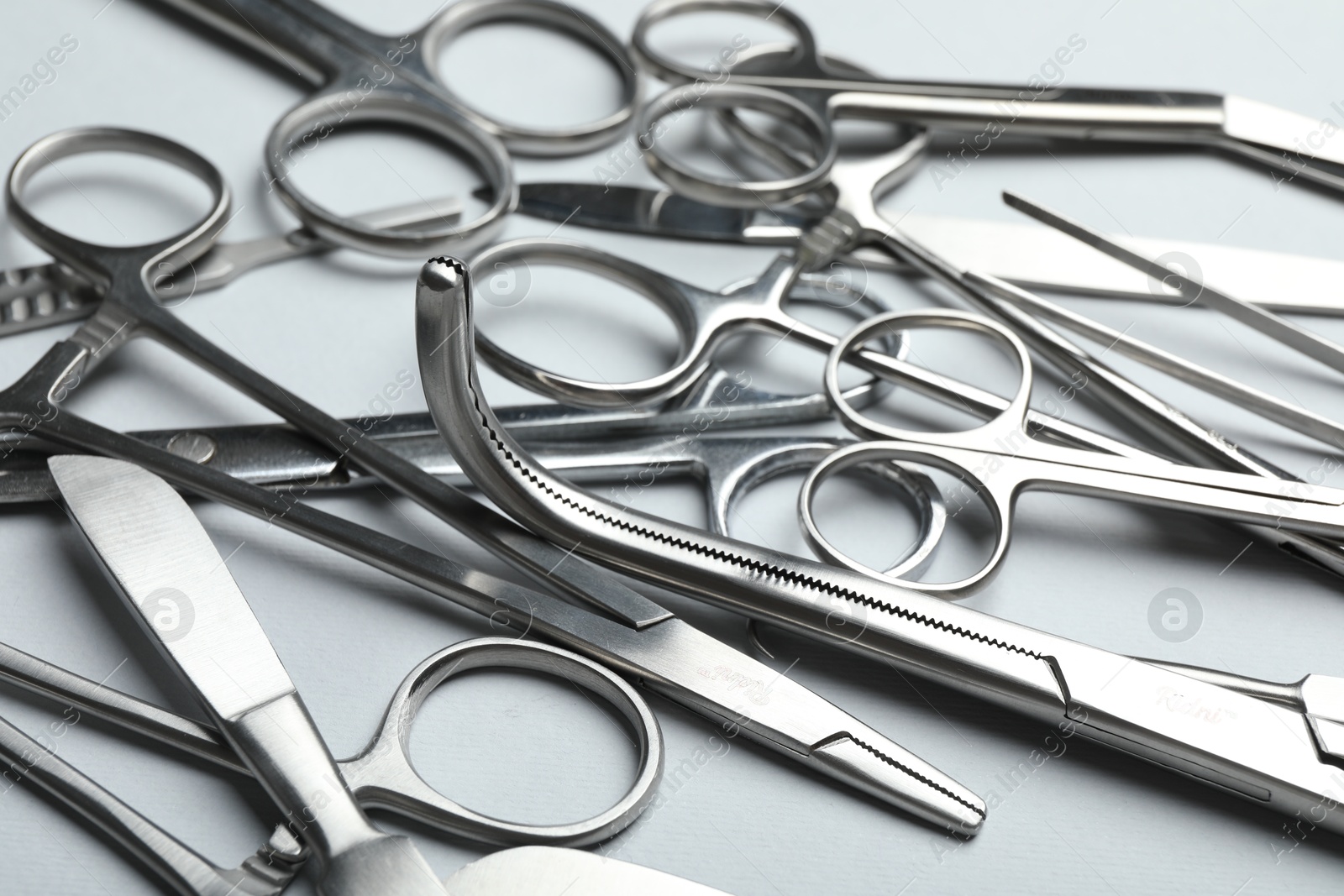 Photo of Different surgical instruments on light grey background, closeup