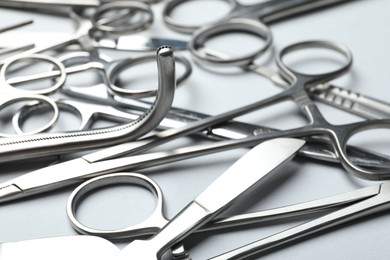 Photo of Different surgical instruments on light grey background, closeup