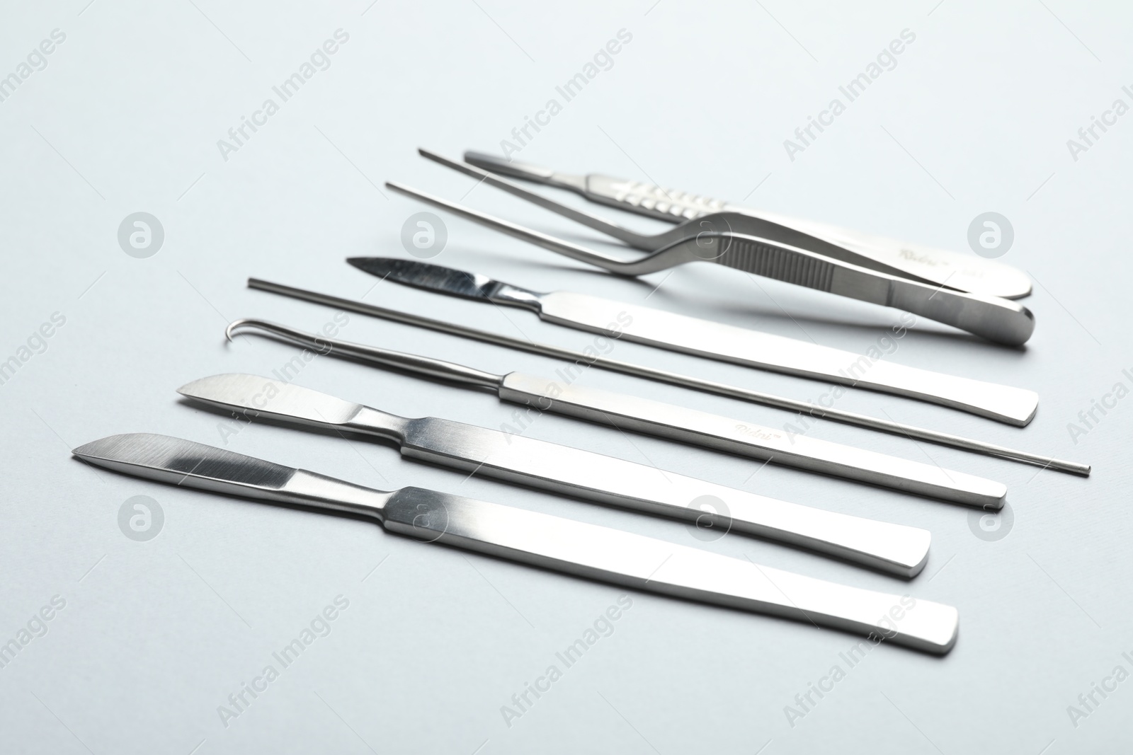 Photo of Different surgical instruments on light grey background, closeup