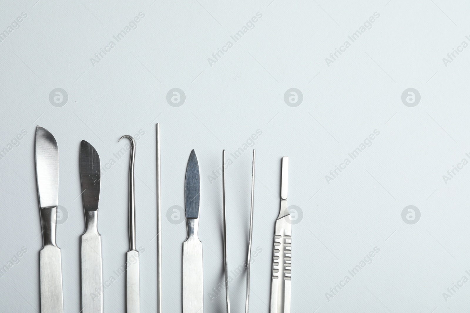 Photo of Different surgical instruments on light grey background, flat lay. Space for text