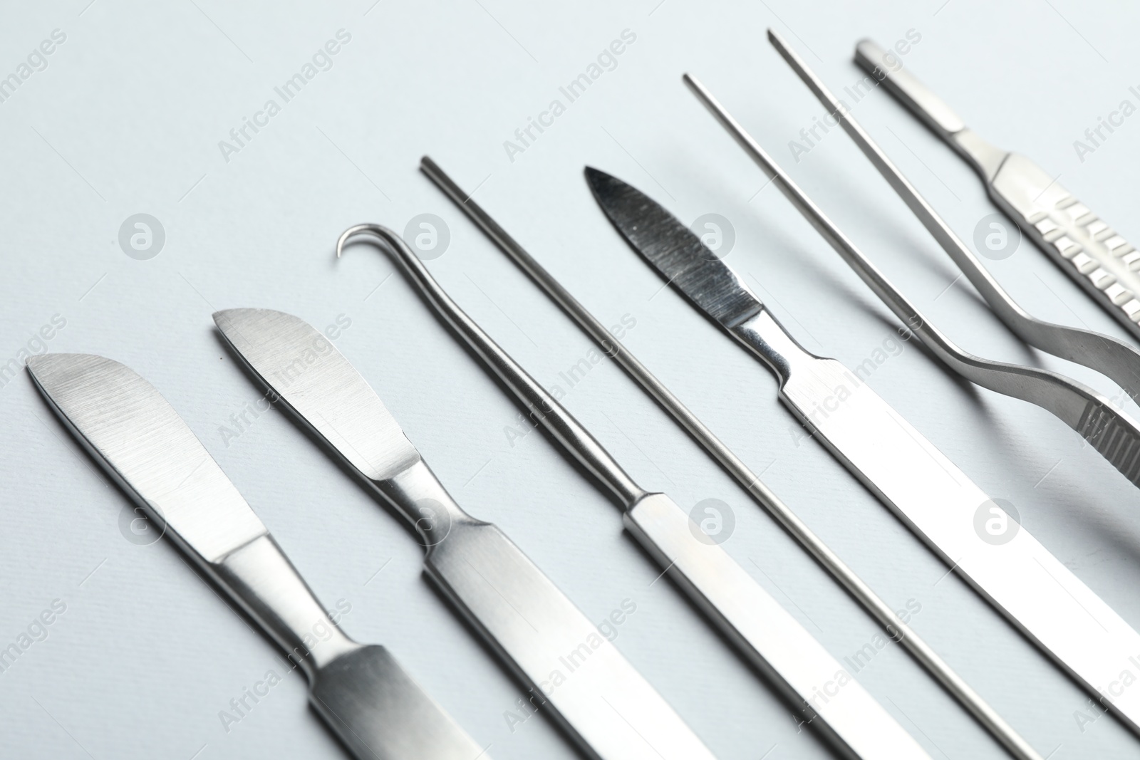 Photo of Different surgical instruments on light grey background, closeup