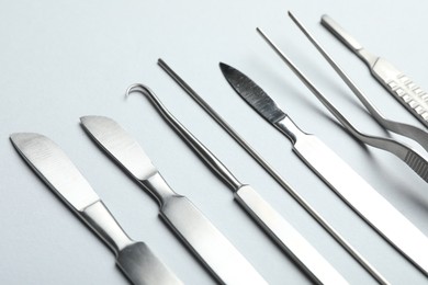 Photo of Different surgical instruments on light grey background, closeup