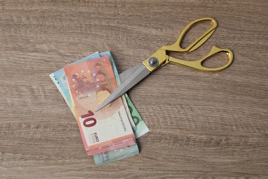 Photo of Euro banknotes and scissors on wooden table, top view