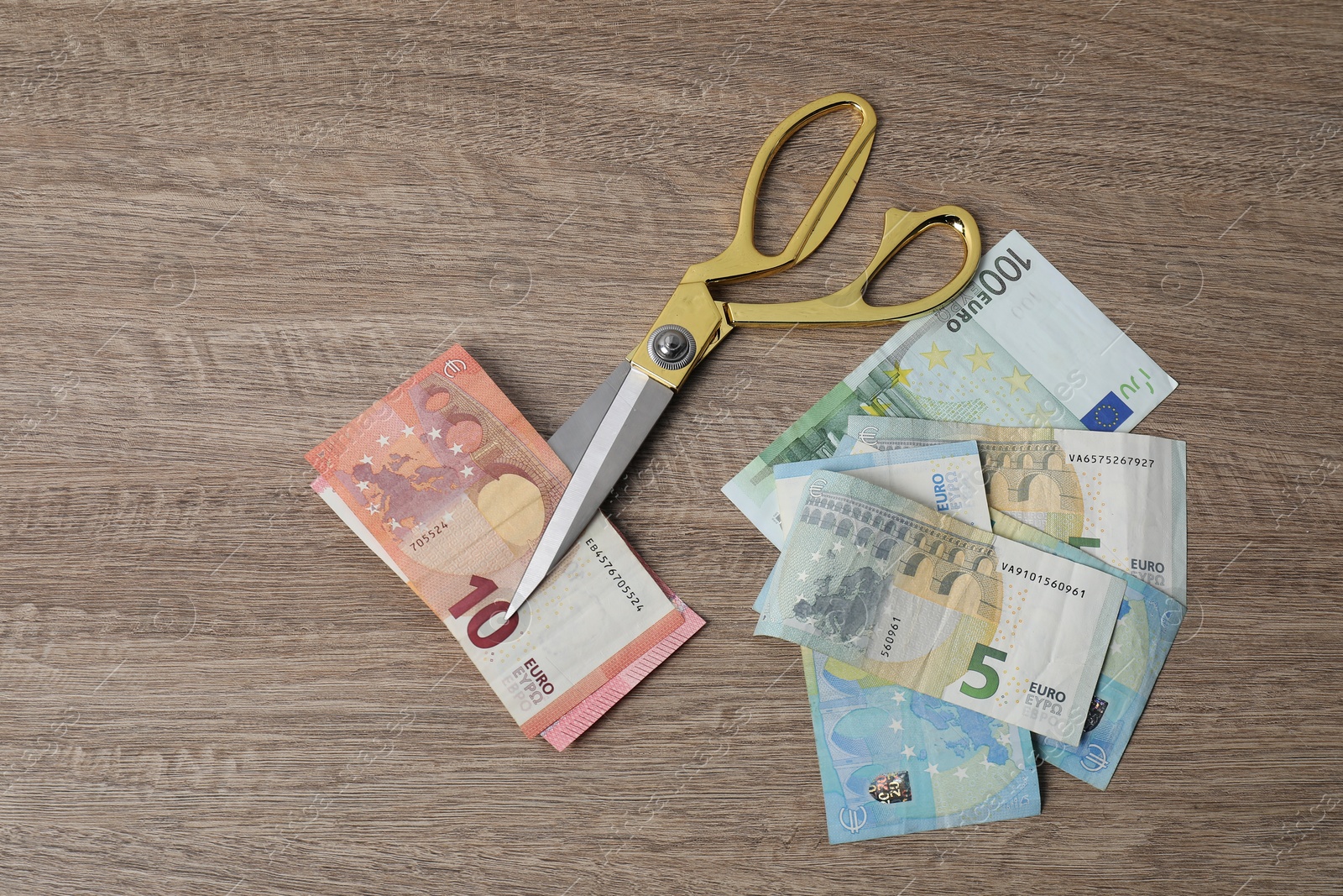 Photo of Euro banknotes and scissors on wooden table, flat lay