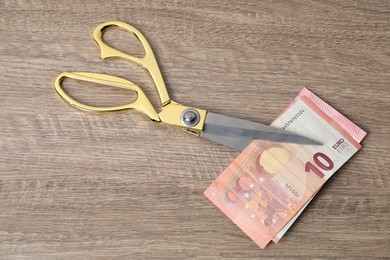 Photo of Euro banknotes and scissors on wooden table, top view