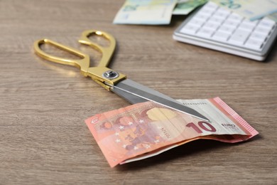 Photo of Euro banknotes and scissors on wooden table, closeup