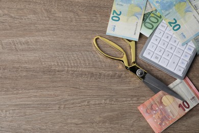 Photo of Euro banknotes, calculator and scissors on wooden table, flat lay. Space for text