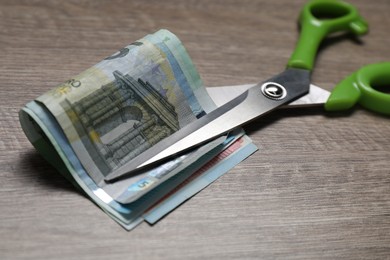 Photo of Euro banknotes and scissors on wooden table, closeup