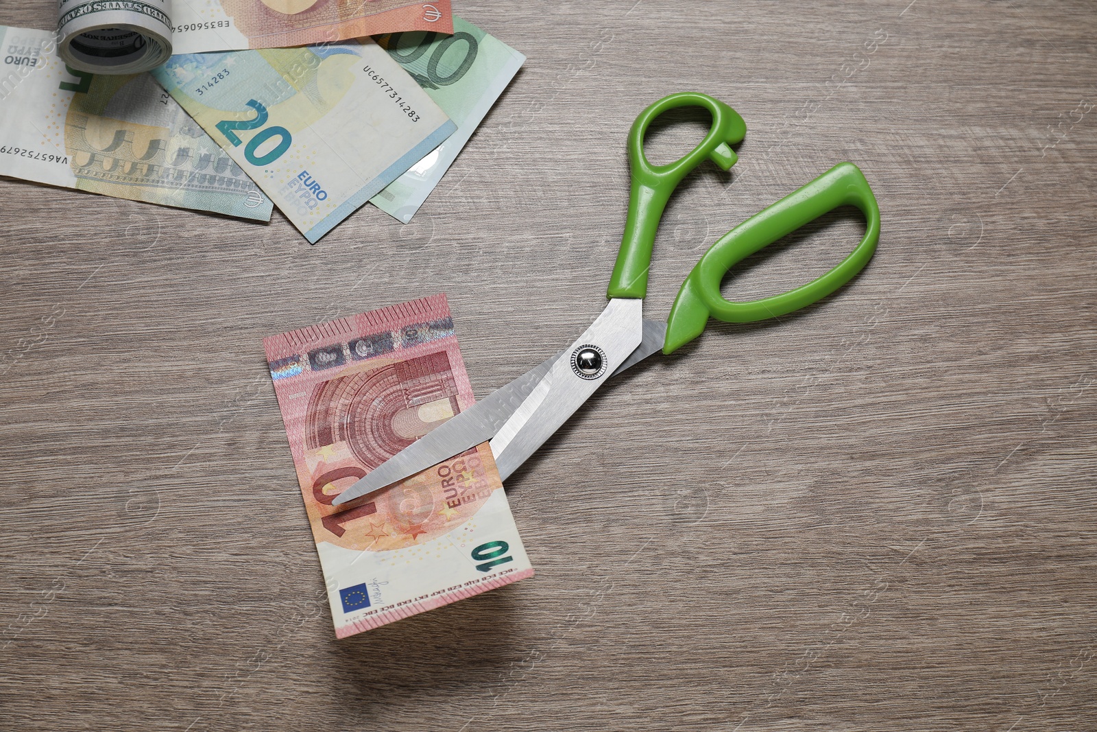 Photo of Euro banknotes and scissors on wooden table, flat lay