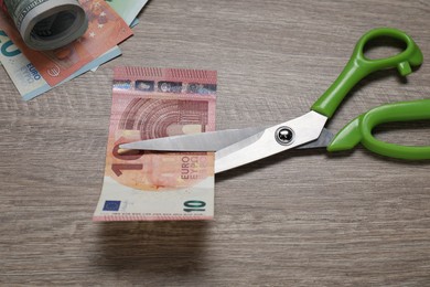 Photo of Euro banknote and scissors on wooden table, closeup