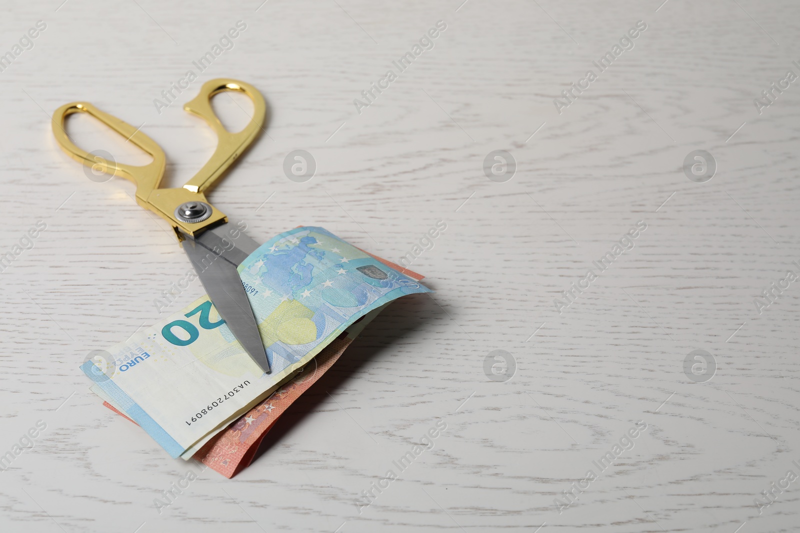 Photo of Euro banknotes and scissors on white wooden table, space for text