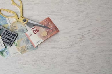 Photo of Euro banknotes, calculator and scissors on white wooden table, flat lay. Space for text