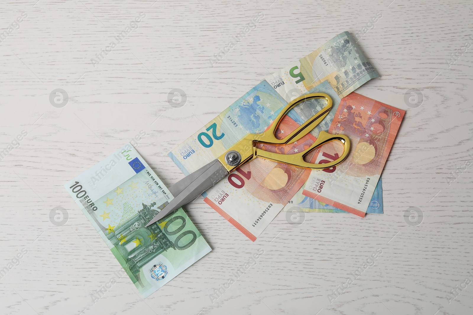 Photo of Euro banknotes and scissors on white wooden table, flat lay