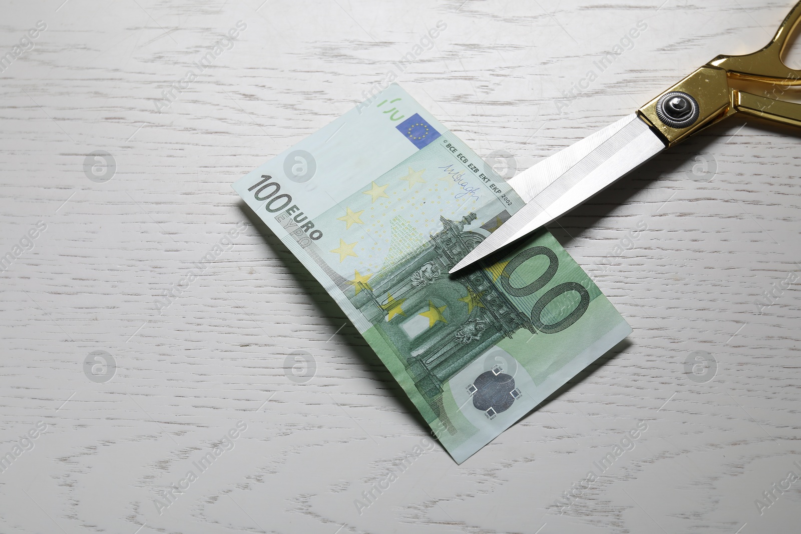 Photo of Scissors with euro banknote on white wooden table, top view. Space for text