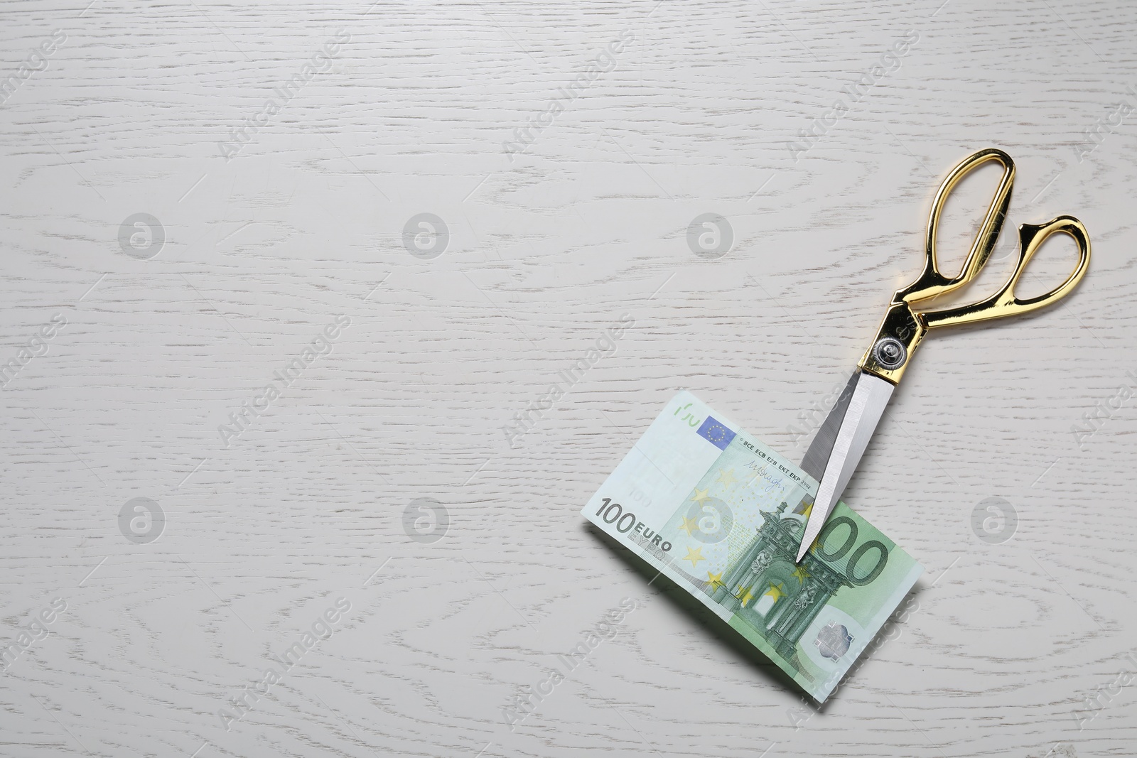 Photo of Scissors with euro banknote on white wooden table, top view. Space for text