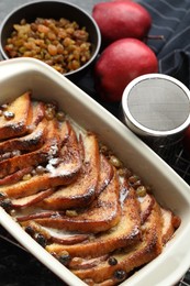 Photo of Freshly baked bread pudding in baking dish, apples and raisins on table, above view