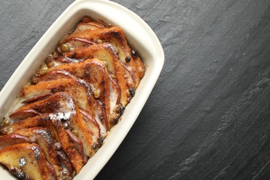 Photo of Freshly baked bread pudding in baking dish on grey textured table, top view. Space for text