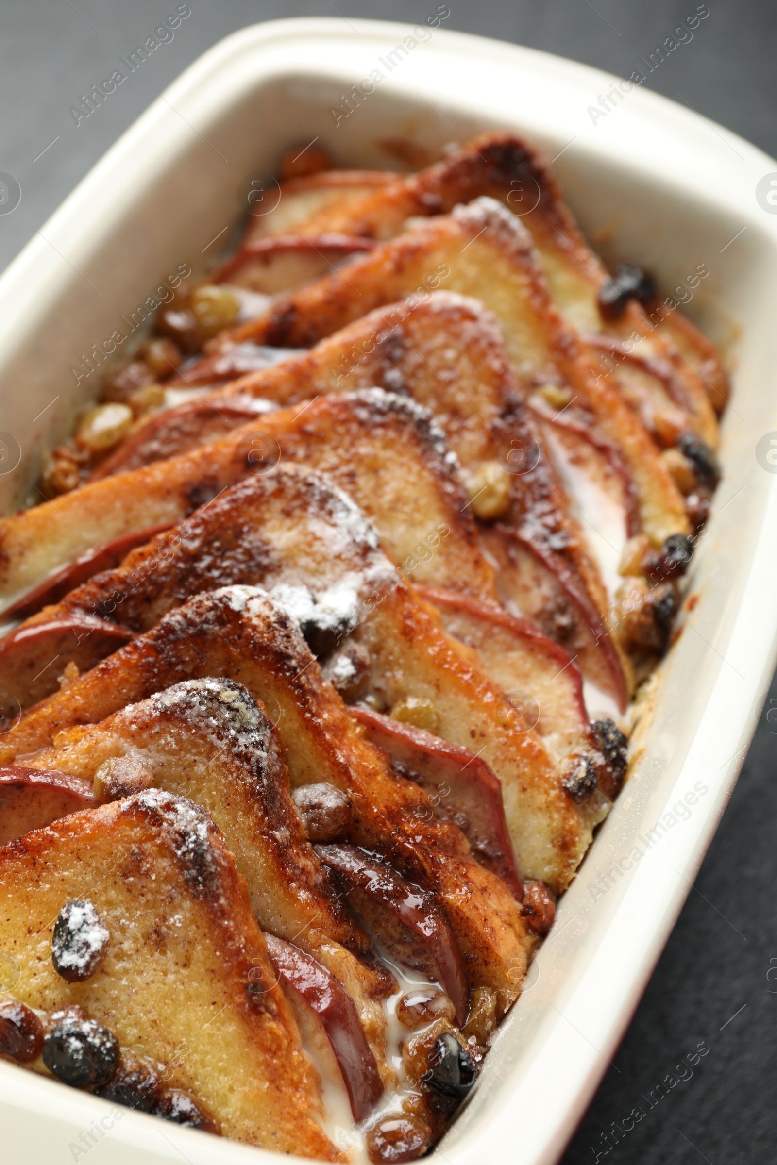 Photo of Freshly baked bread pudding in baking dish on grey table, closeup