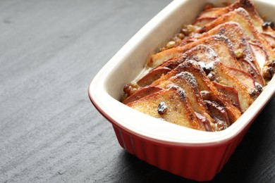 Photo of Freshly baked bread pudding in baking dish on grey textured table, closeup. Space for text