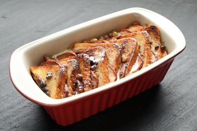 Photo of Freshly baked bread pudding in baking dish on grey textured table, closeup