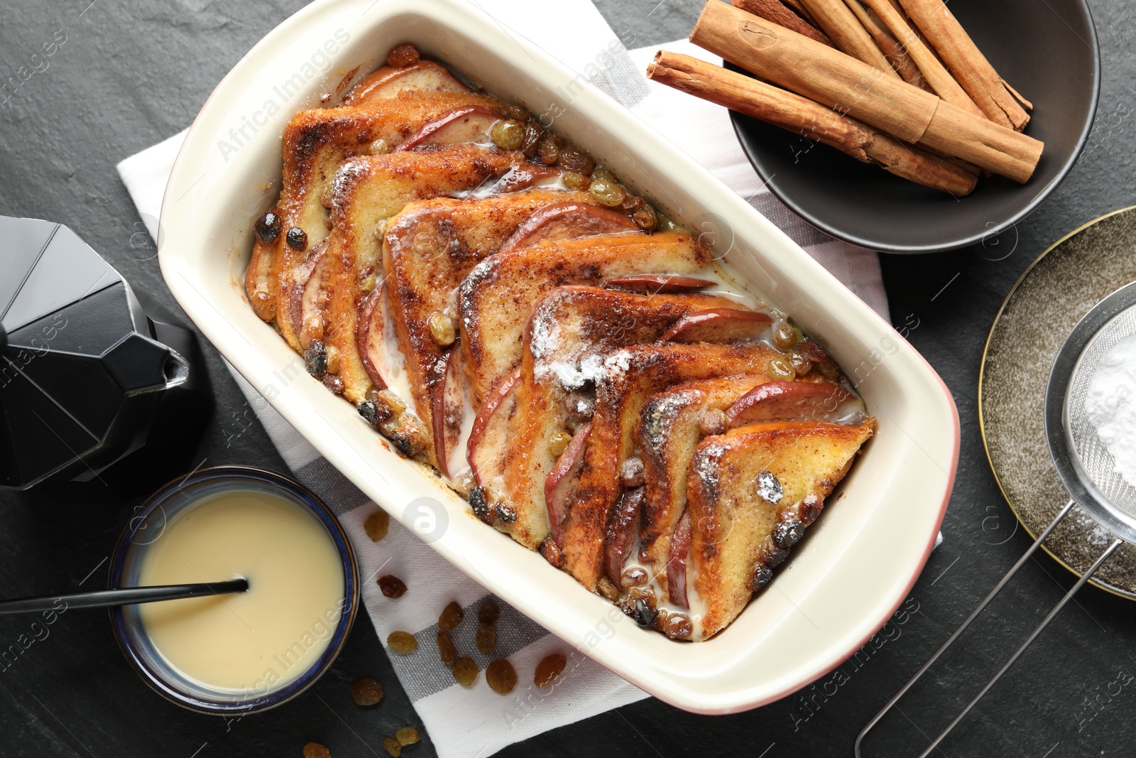 Photo of Flat lay composition with freshly baked bread pudding on dark textured table