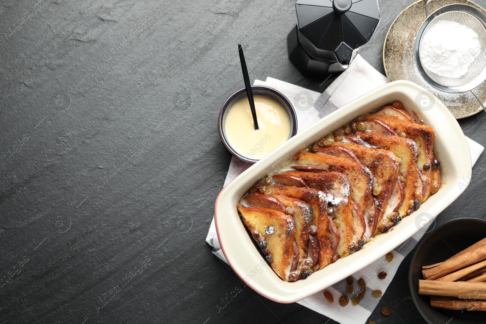 Photo of Flat lay composition with freshly baked bread pudding on dark textured table. Space for text