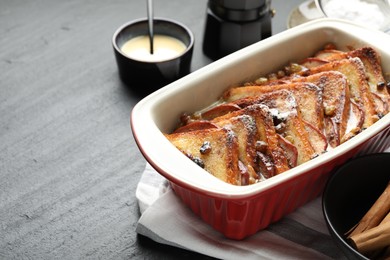 Photo of Freshly baked bread pudding in baking dish on dark textured table, closeup. Space for text