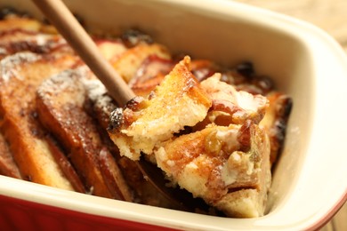 Photo of Taking tasty bread pudding from baking dish, closeup