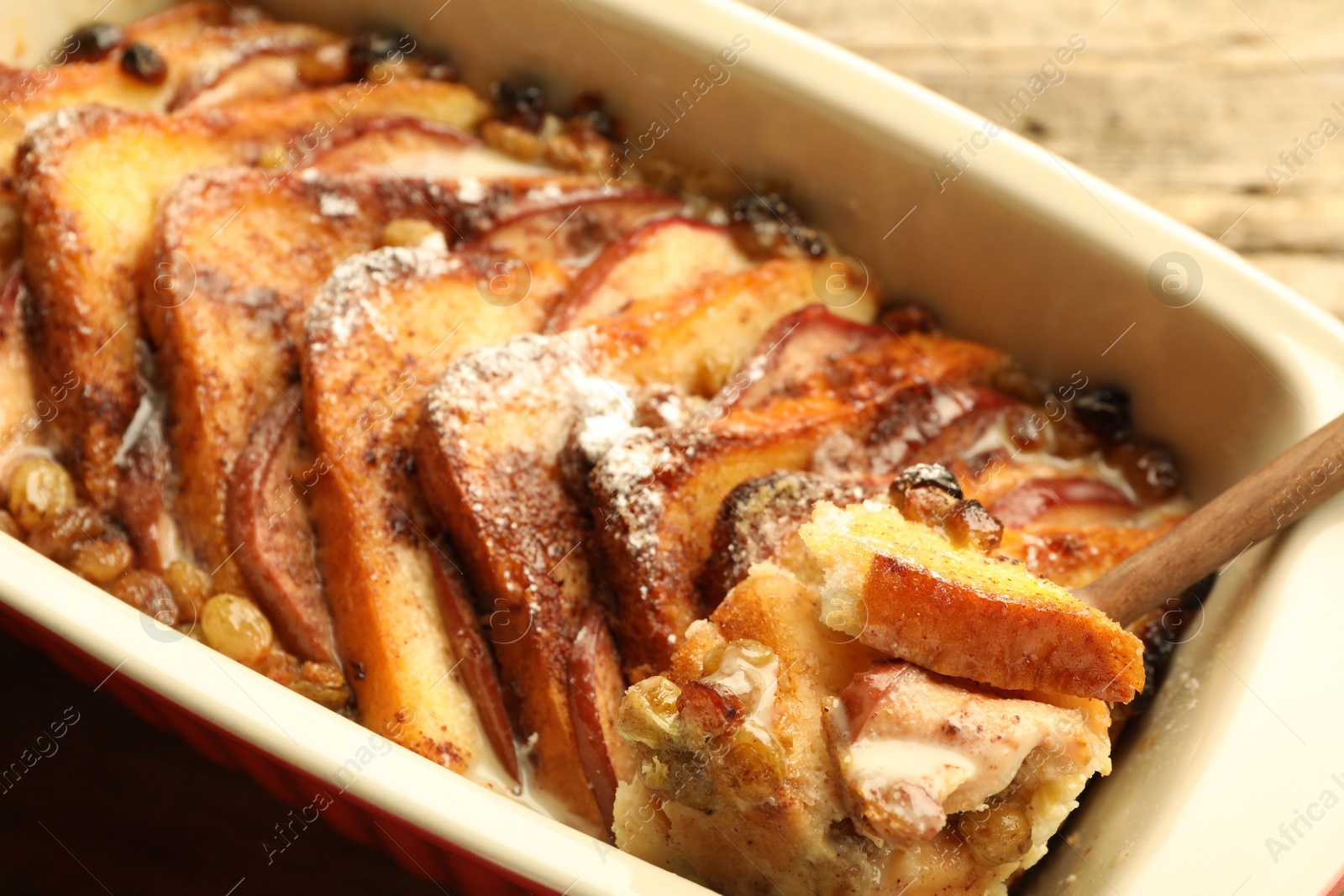 Photo of Taking tasty bread pudding from baking dish, closeup