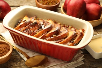 Photo of Freshly baked bread pudding in baking dish and products on wooden table, closeup