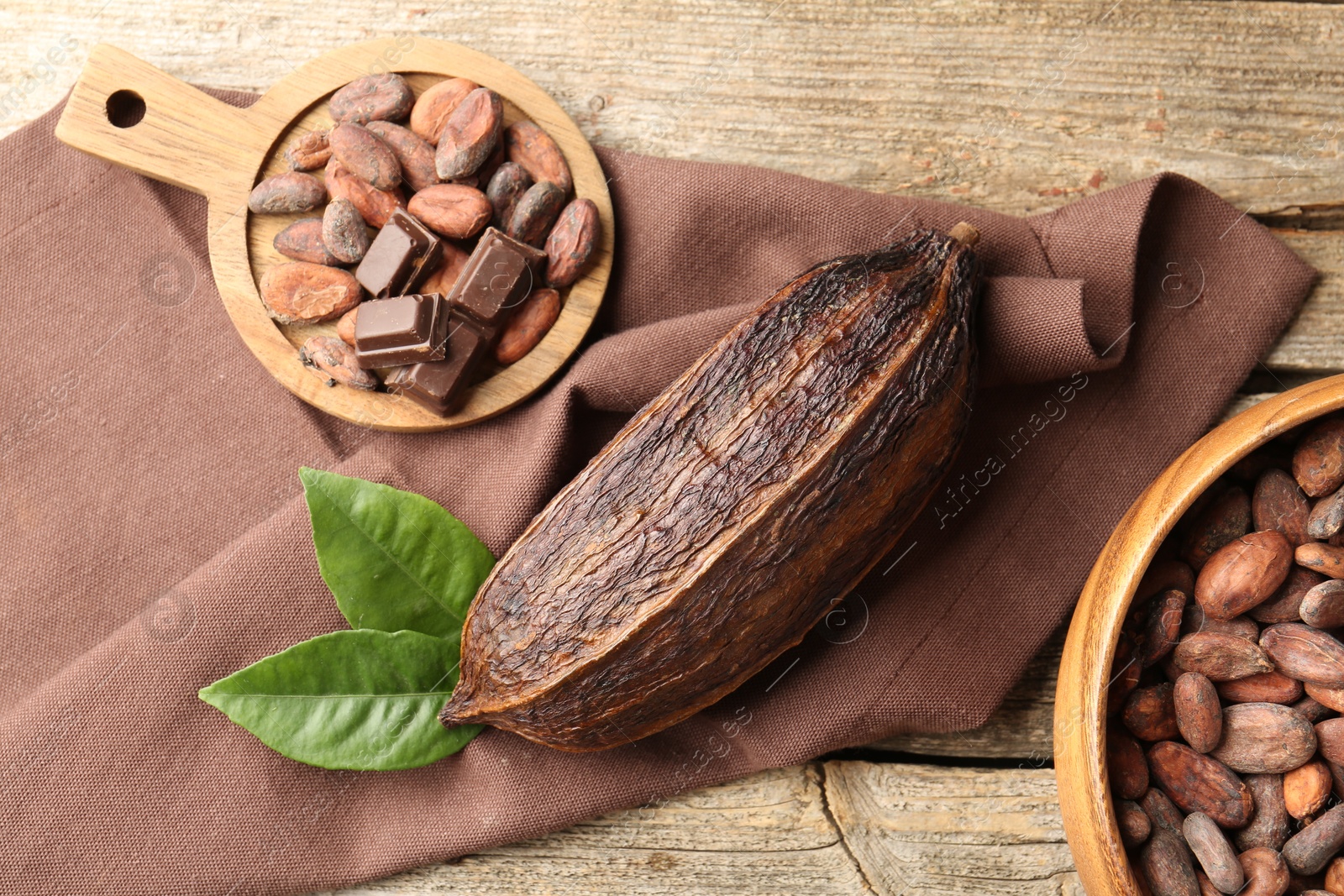 Photo of Cocoa pod and beans on wooden table, flat lay