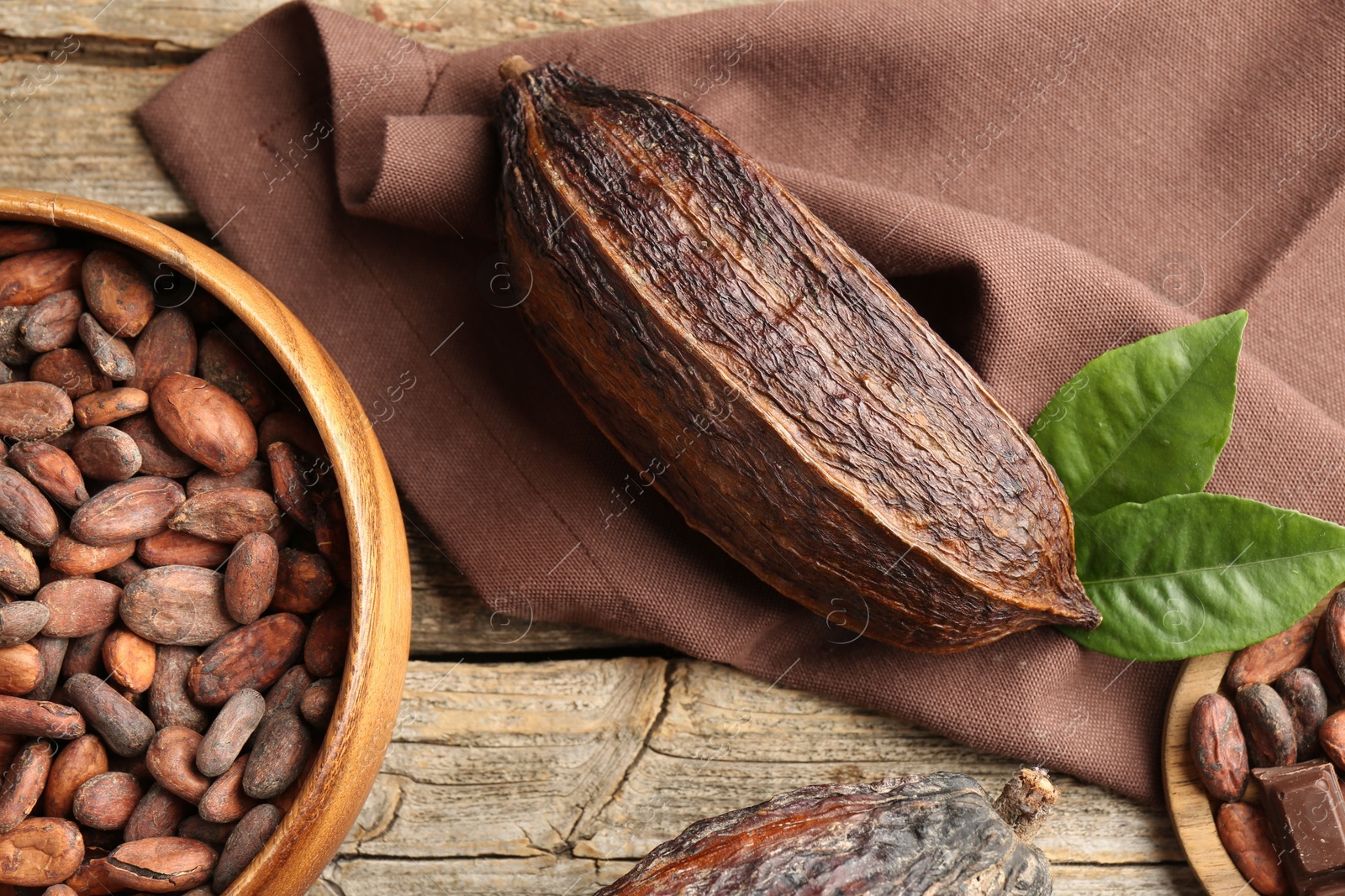 Photo of Cocoa pod and beans on wooden table, flat lay