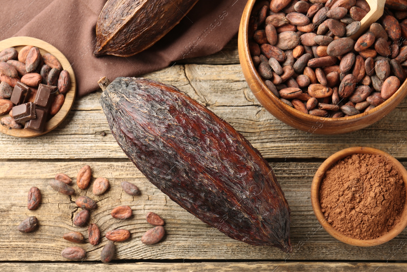 Photo of Cocoa pod, powder and beans on wooden table, flat lay