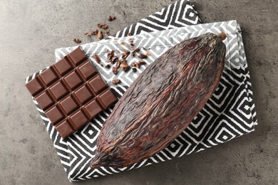 Photo of Cocoa pod and chocolate on grey table, top view