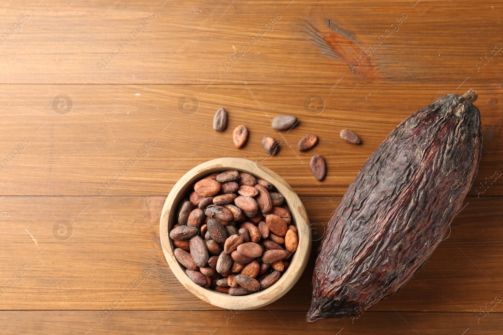 Photo of Cocoa pod and beans on wooden table, flat lay. Space for text