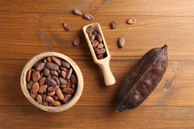 Photo of Cocoa pod and beans on wooden table, flat lay