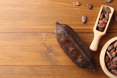 Photo of Cocoa pod and beans on wooden table, flat lay. Space for text