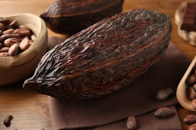 Photo of Cocoa pods and beans on wooden table, closeup