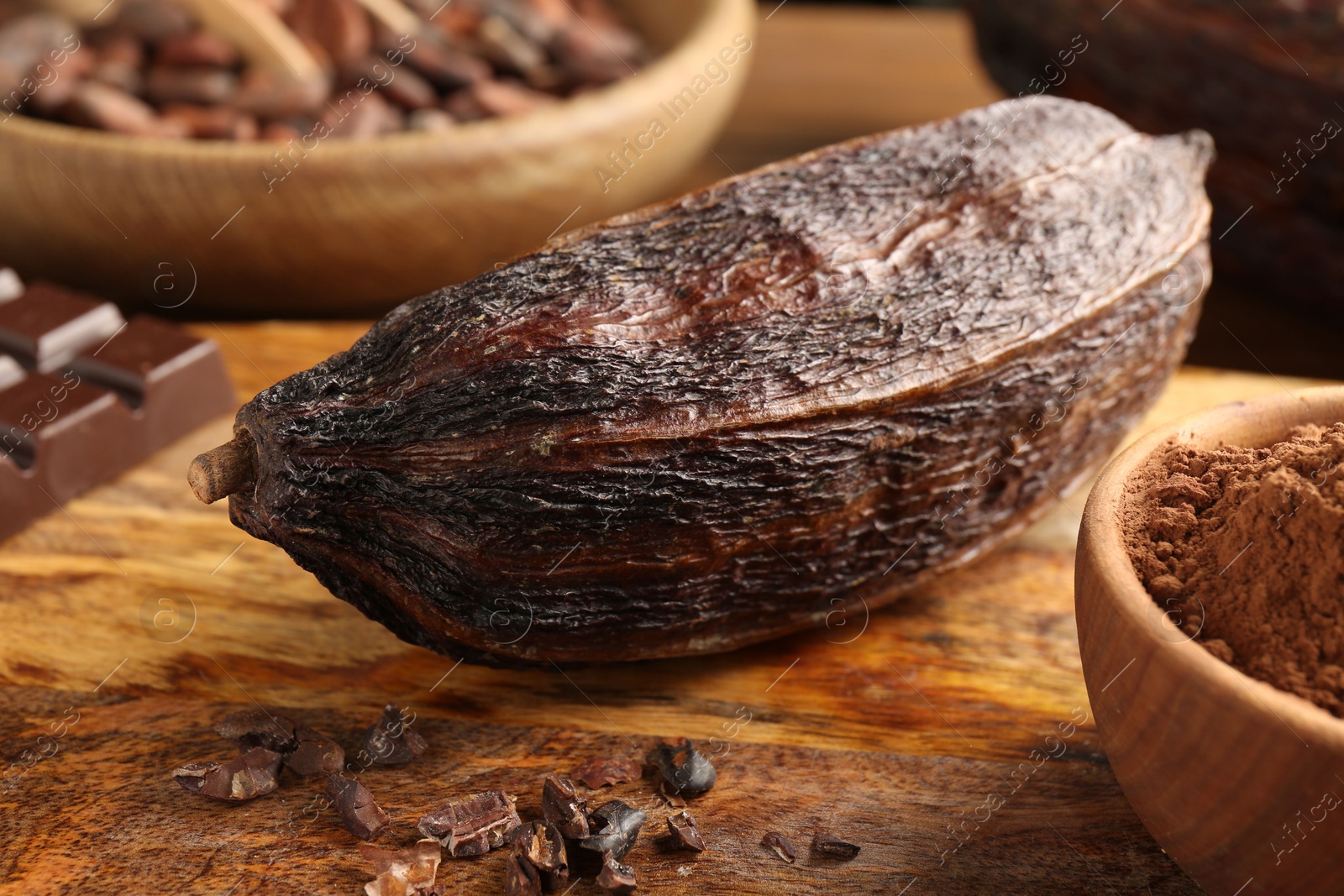 Photo of Cocoa pod, beans, powder and chocolate on wooden table, closeup