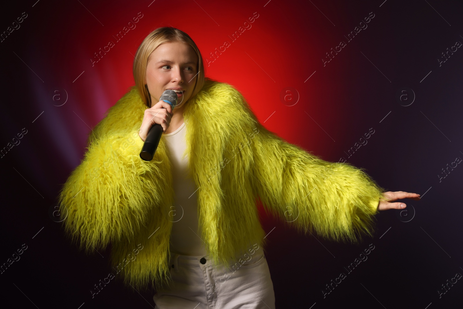 Photo of Talented singer in faux fur performing on dark background with red light