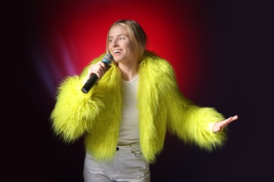 Photo of Talented singer in faux fur performing on dark background with red light