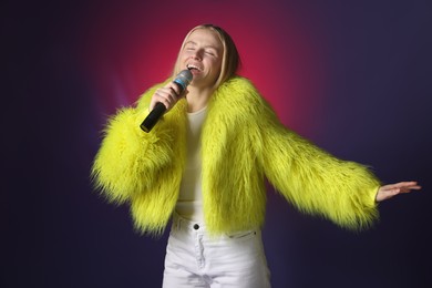 Photo of Talented singer in faux fur performing on dark background with pink light