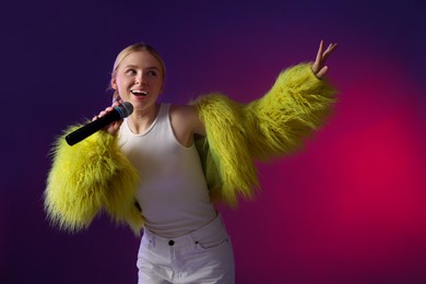 Photo of Talented singer in faux fur performing on purple background with pink light