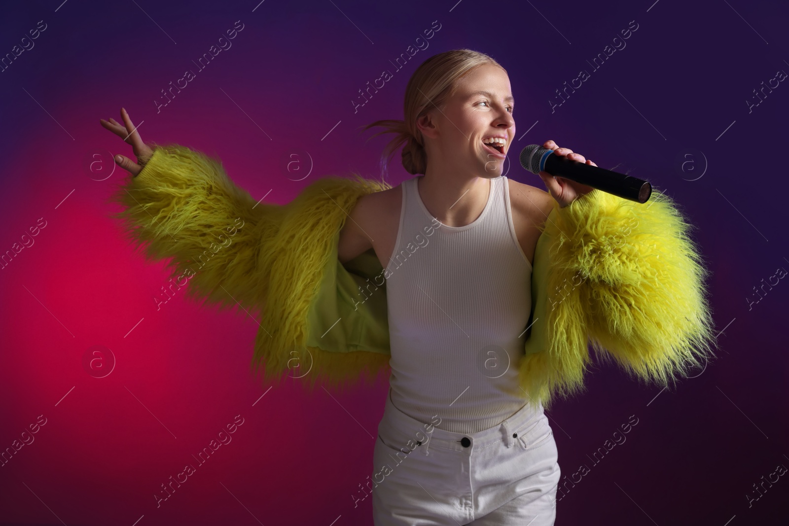 Photo of Talented singer in faux fur performing on purple background with pink light