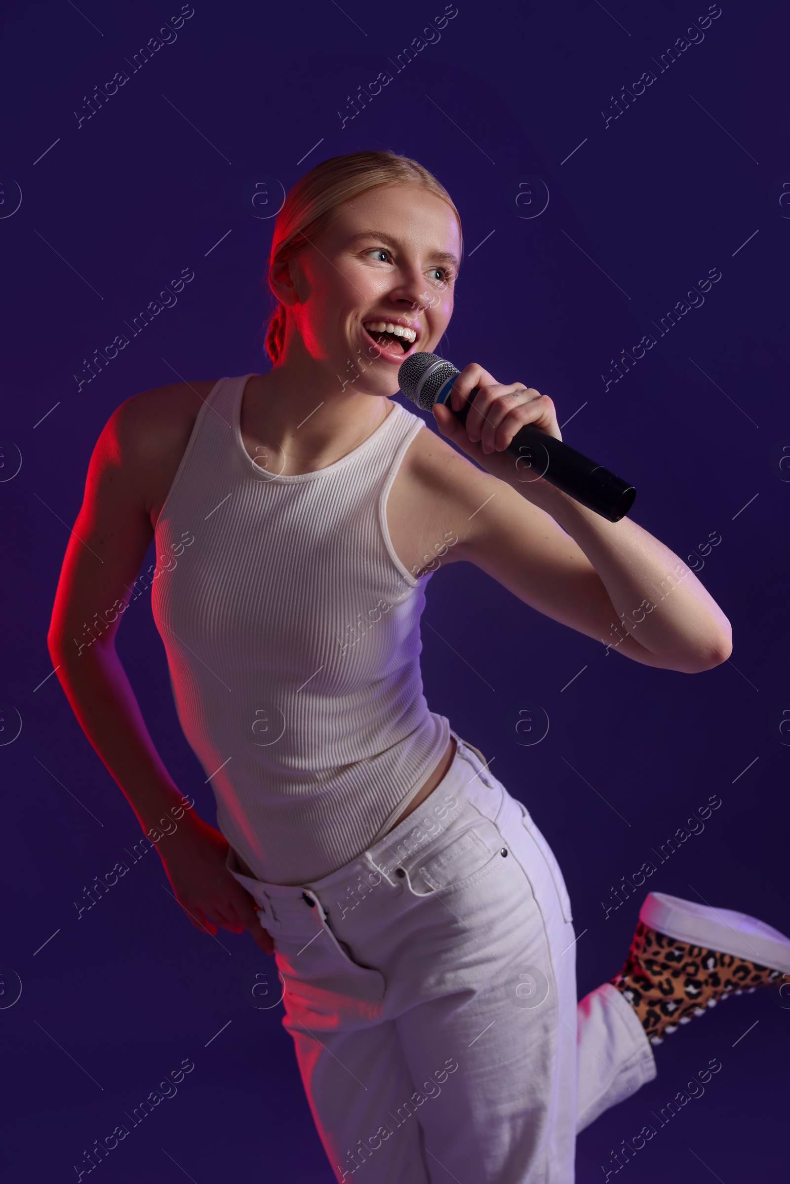 Photo of Beautiful talented singer performing on purple background