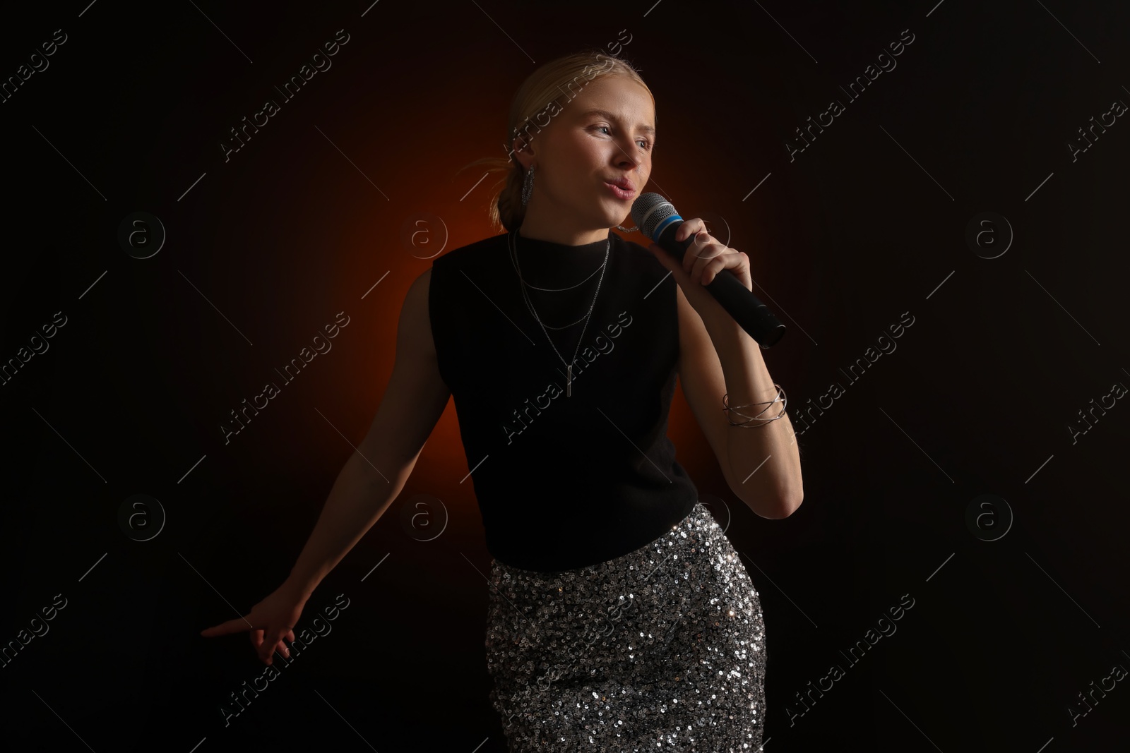 Photo of Beautiful singer performing on dark background with color light